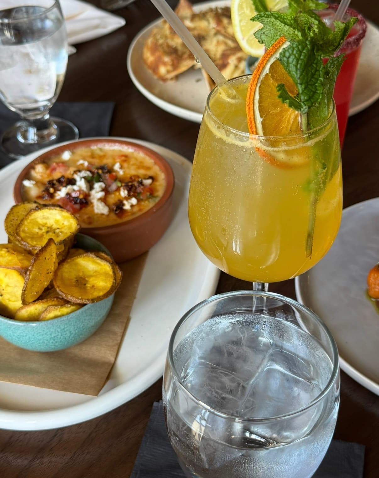 Cheesy shrimp fondue with a side of plantain chips and a citrus cocktail